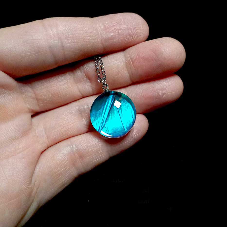 Morpho menelaus butterfly wing necklace shown worn on hand for scale