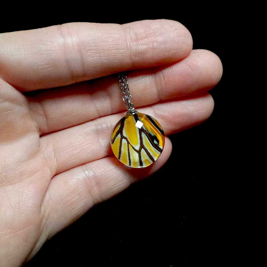 Collana con vera ala di farfalla Danaus genutia mostrata sulla mano con ciondolo di farfalla tigre comune
