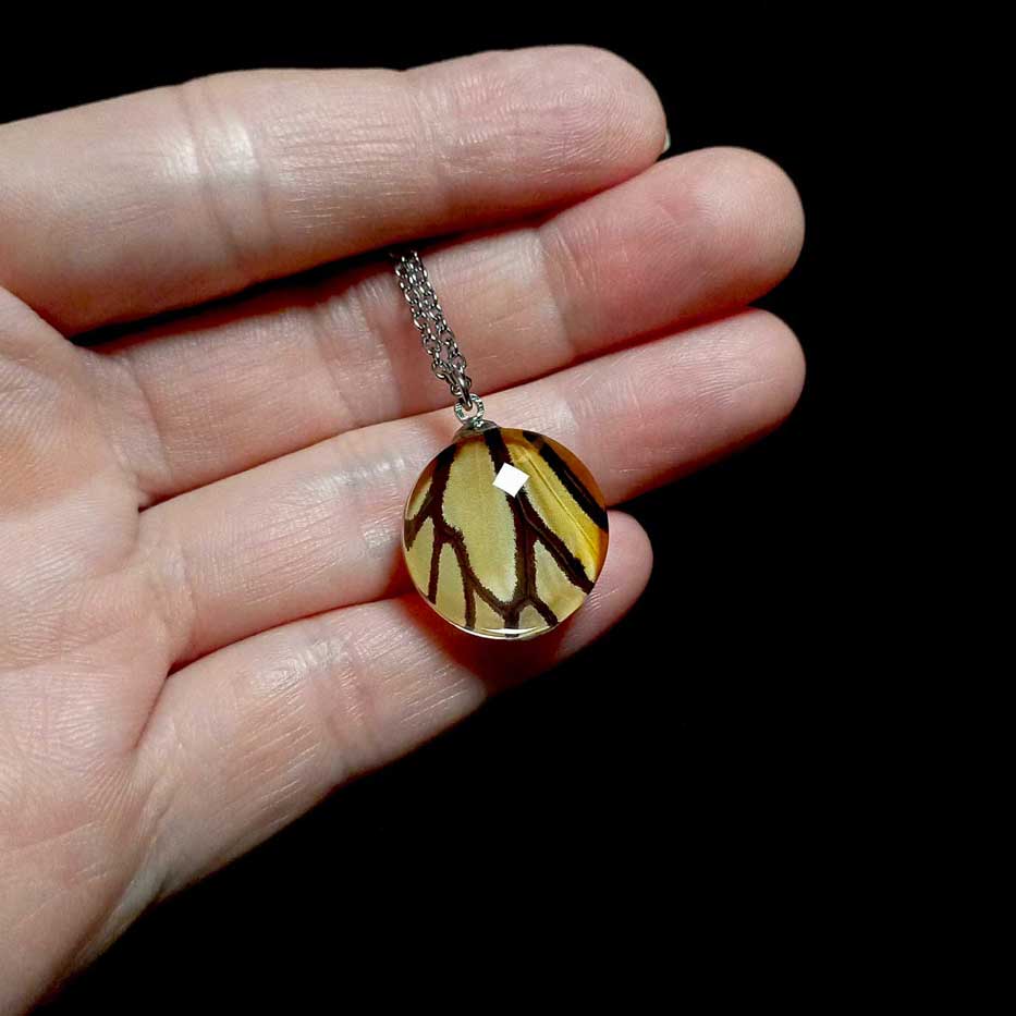 Collana con vera ala di farfalla Danaus plexippus mostrata sulla mano con ciondolo arancione e nero di farfalla monarca