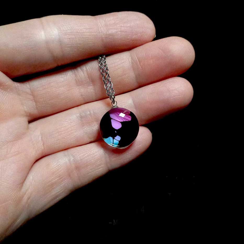 Collana con vera ala di farfalla Graphium weiskei mostrata sulla mano con ciondolo con ala di farfalla macaone con macchie viola